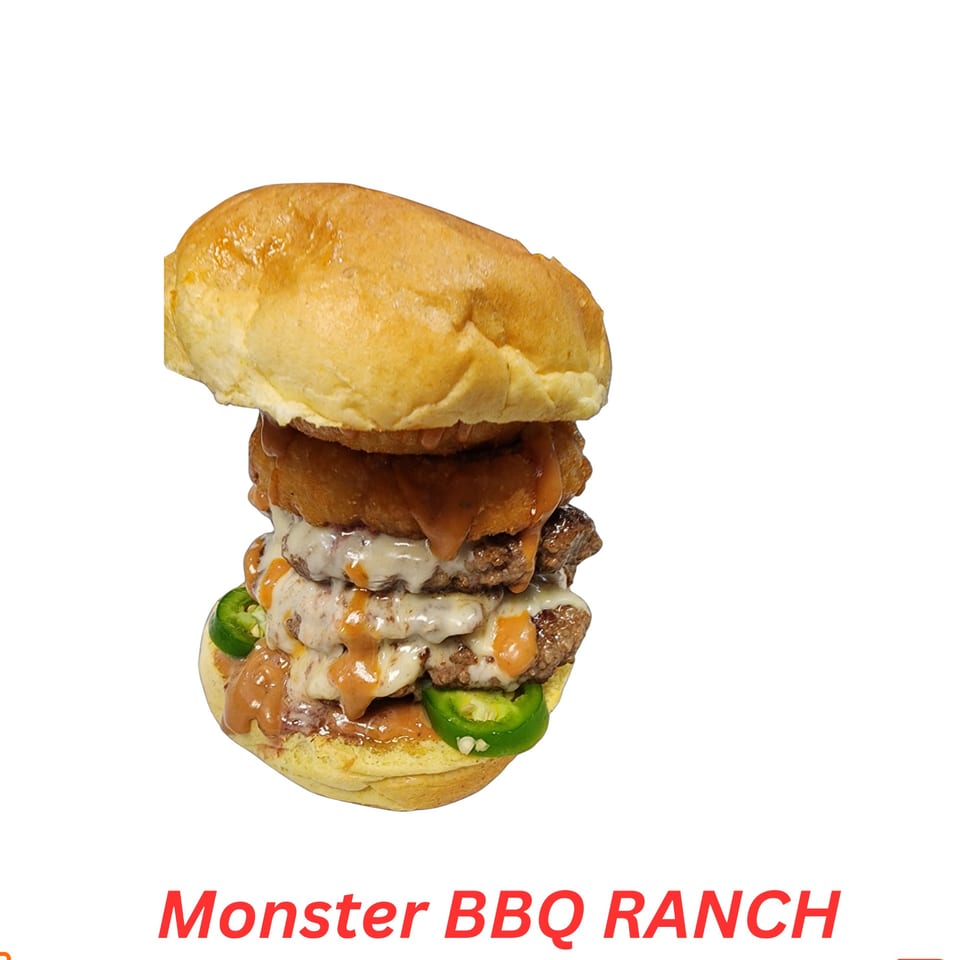 A towering Monster BBQ Ranch burger with multiple patties, cheese, onion rings, and jalapeños.