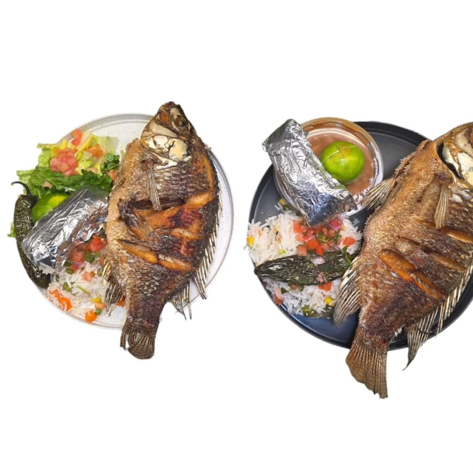 Two plates of whole fried fish, rice, salad, lime, and a jalapeño, served halal style.