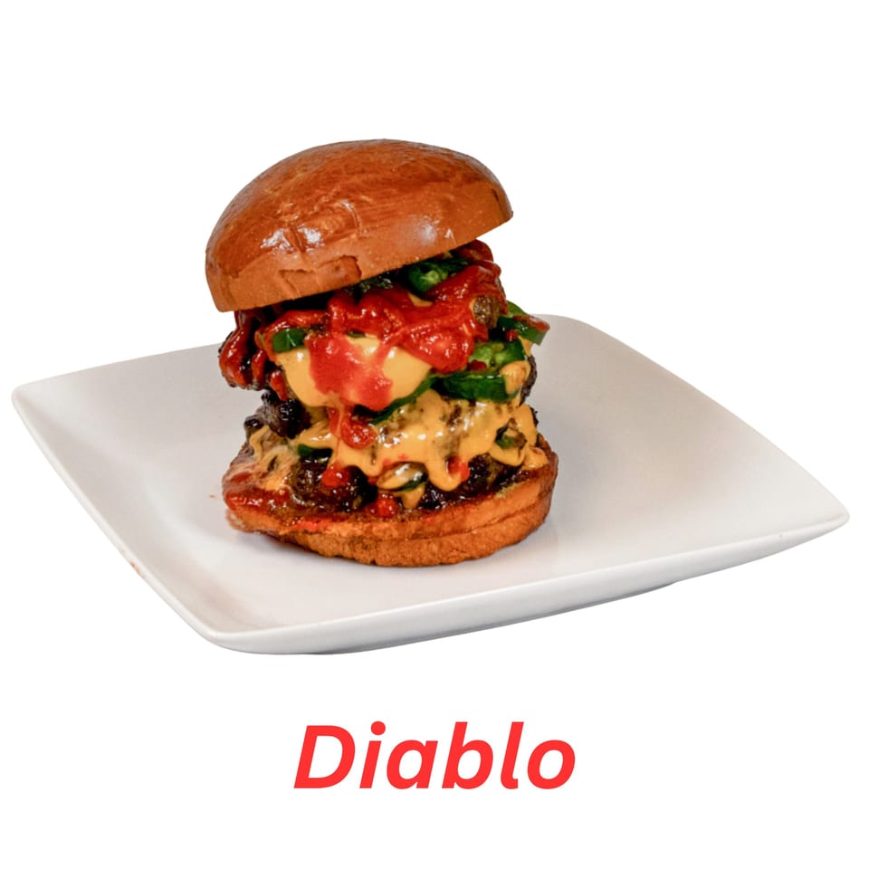 A towering Diablo burger with double patties, melted cheese, red sauce, and green peppers on a white plate.