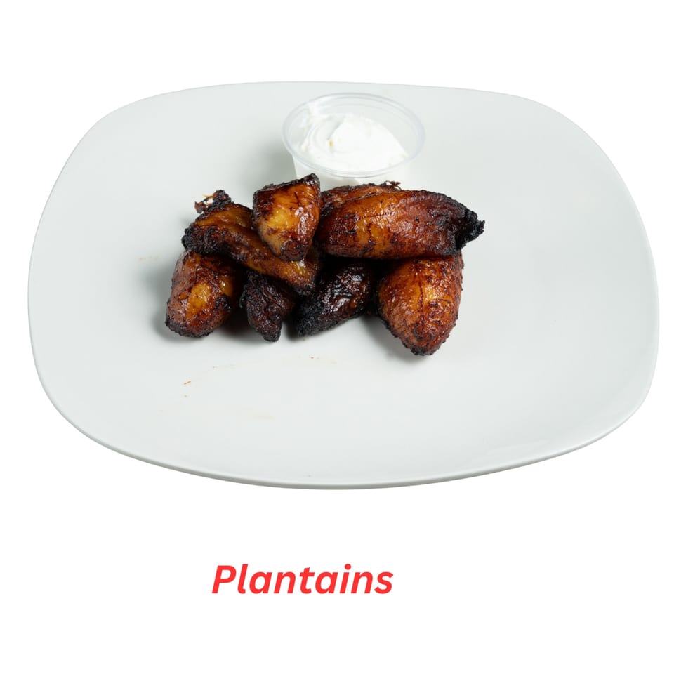 A white plate holds a serving of dark brown fried plantains with a side of white dipping sauce.