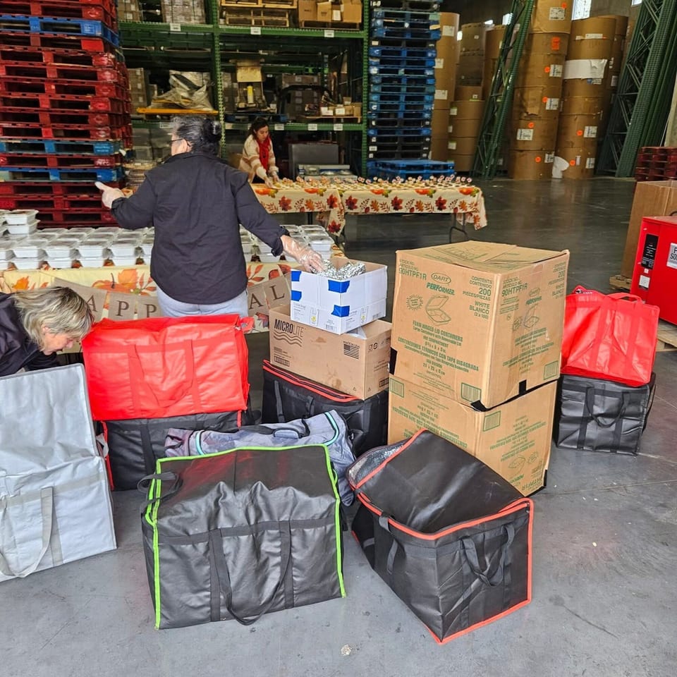 Workers prepare numerous packaged halal meals for delivery in a warehouse setting.